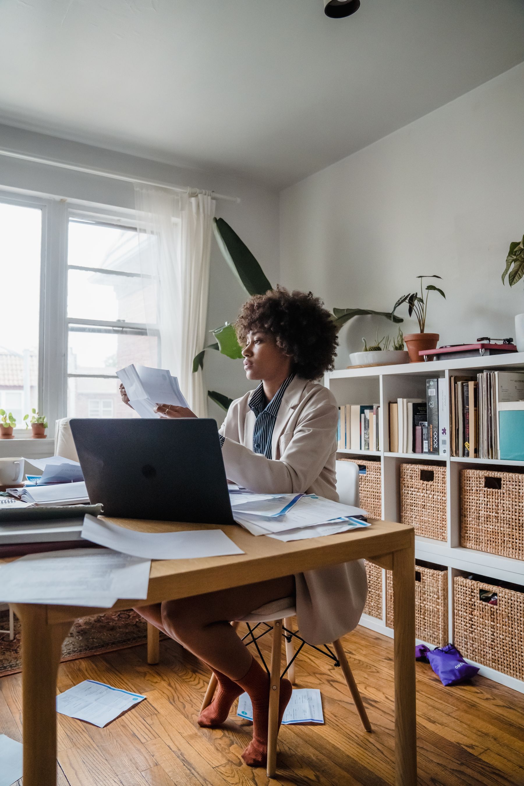 A person sorting through their records at home beside a laptop